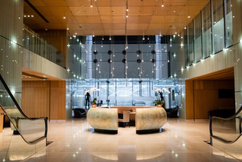 A fancy building’s lobby is illuminated by pendant lights.