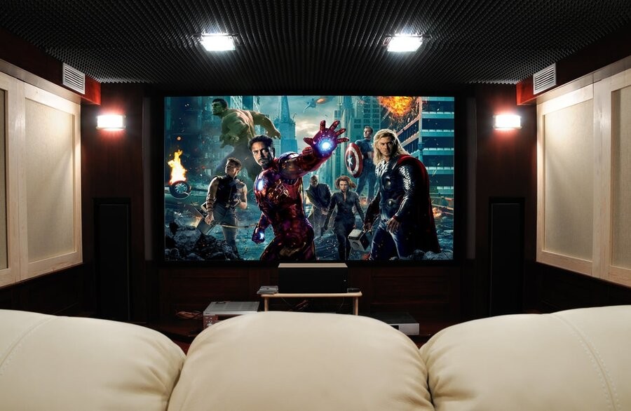 A home theater setup featuring comfy seating, acoustic treatments, and a large screen showing The Avengers (2012).