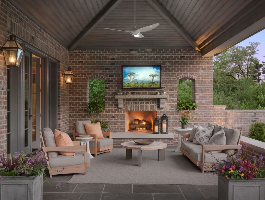 A covered patio with a center table, seats, fireplace, and TV