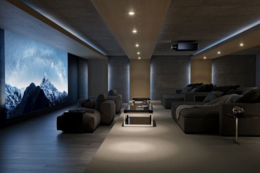 A large home theater with gray loveseats and a movie screen depicting snowy mountains.