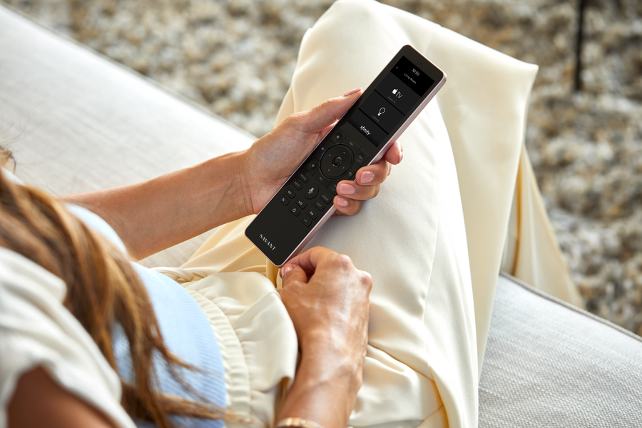 a woman sitting on a sofa holding a smart remote 