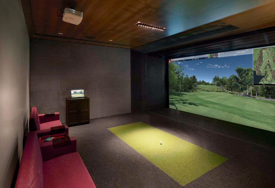 A golf simulator featuring a virtual caddy kiosk and ceiling projector. 